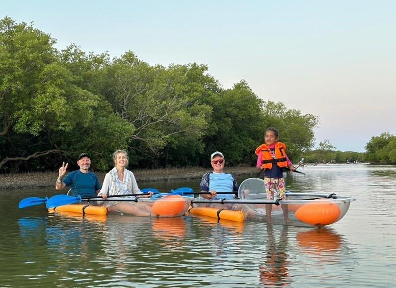 A group of people in a canoe on a calm river surrounded by mangrove trees. 1