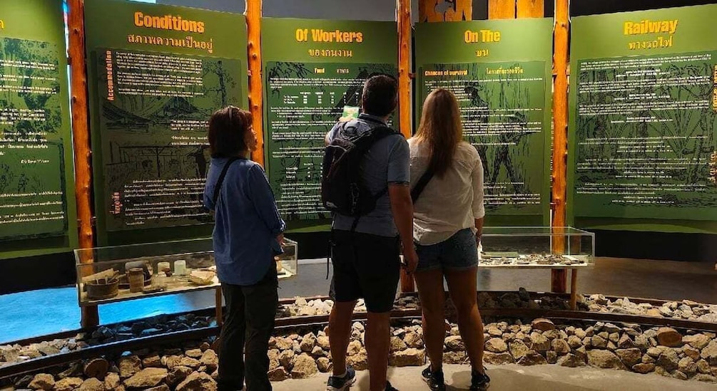 A group of people standing in front of informational displays about workers and railway conditions. 4