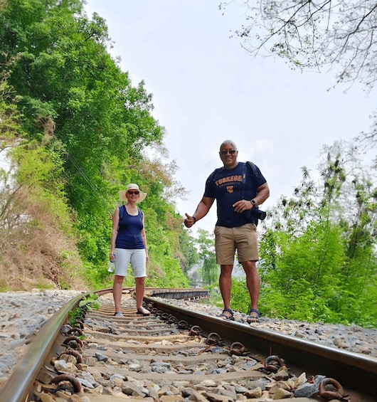 Two people standing on a railway track surrounded by greenery. 2