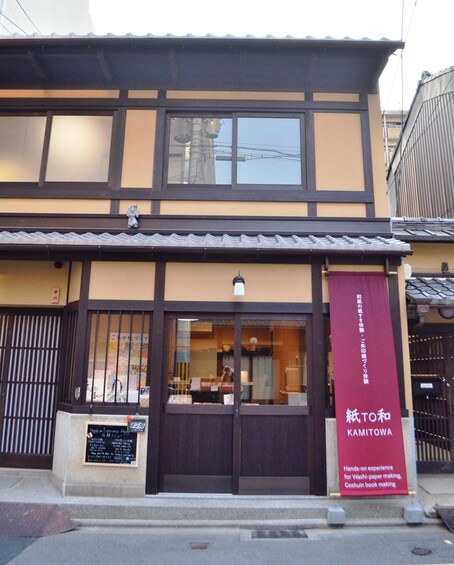 Ein traditionelles japanisches Gebäude mit einem Schild für 'KAMITOWA', das die Möglichkeit bietet, die Herstellung von Washi-Papier und Goshuin-Büchern selbst auszuprobieren. 3