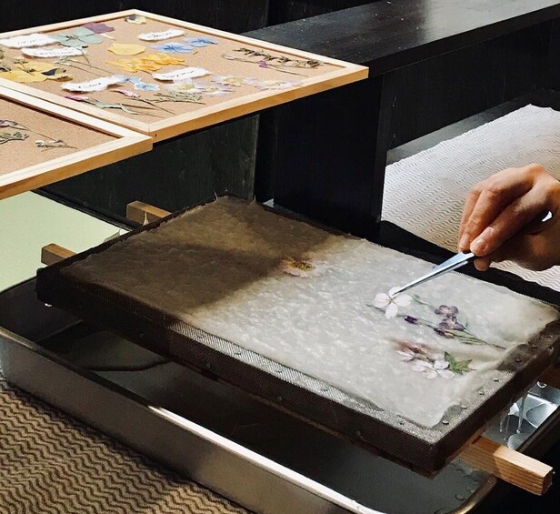 Eine Person arbeitet an einer botanischen Illustration in einem Rahmen und benutzt eine Lupe. 5