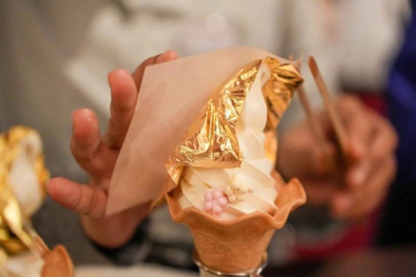 Iemand houdt een dessert vast met een gouden verpakking. 4