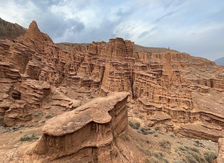 A rugged canyon landscape with layered rock formations and a prominent rock outcrop in the foreground. 1