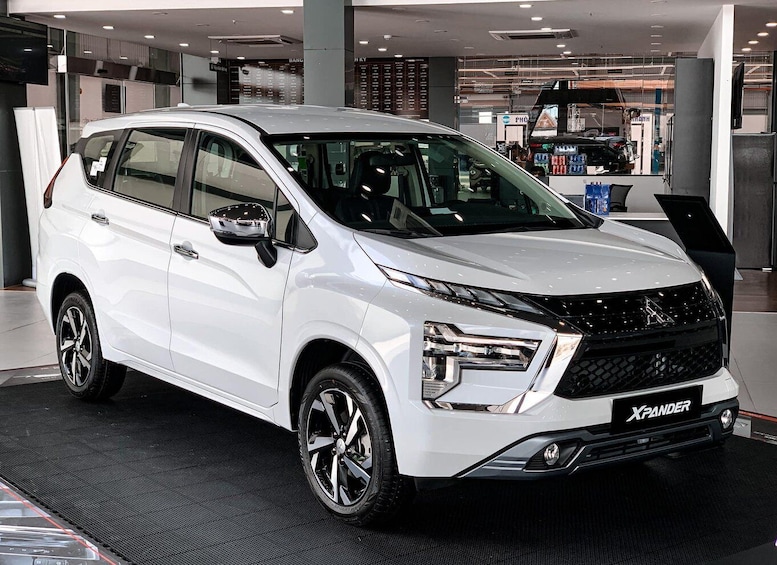 Un SUV blanc, arborant le logo « X-PANDER », est garé à l’intérieur, probablement dans une salle d’exposition. 2