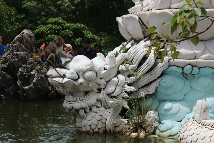Une grande sculpture de dragon, placée dans un plan d’eau, avec des personnes autour. 1