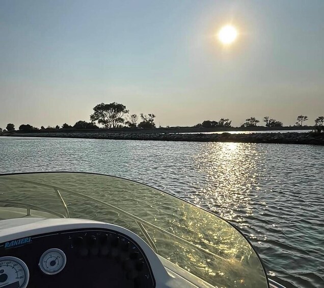 A boat on calm water with a clear sky and the sun reflecting off the surface. 3