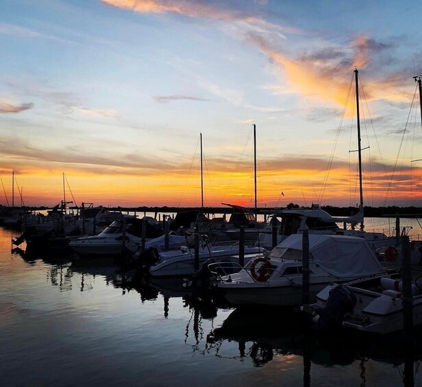 A marina at sunset with boats docked and calm water reflecting the sky. 5