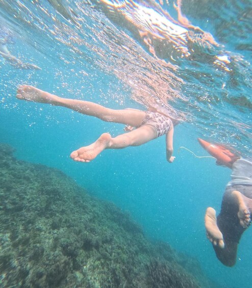 A person swimming underwater with another individual above water. 3