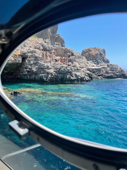 A rocky coastline with clear blue waters and a group of people on the rocks. 2
