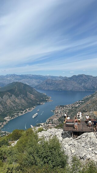A mountainous landscape with a lake, a town, and a wooden viewing platform. 4