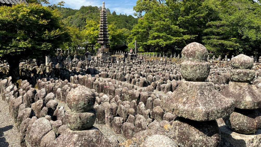 A cemetery with numerous stone statues and a pagoda in the background. 3