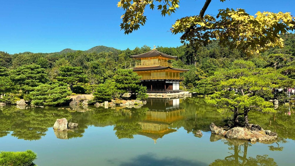 A traditional Japanese building surrounded by a tranquil pond, with lush greenery and mountains in the background. 2