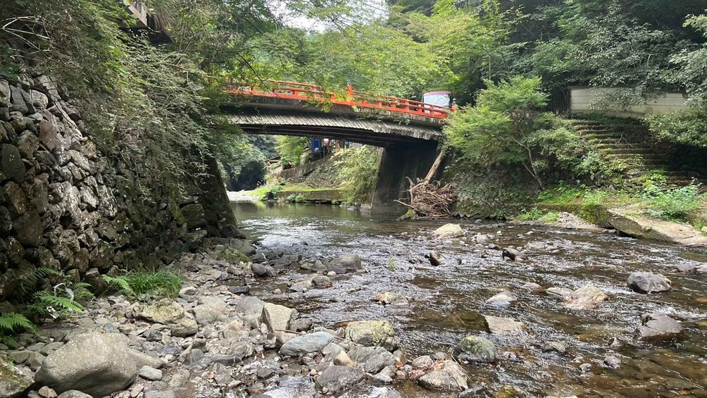 A stone bridge over a rocky stream in a forested area. 1