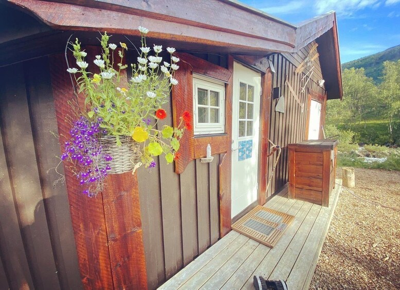 A wooden cabin with a porch, a hanging flower basket, and a wooden door. 3
