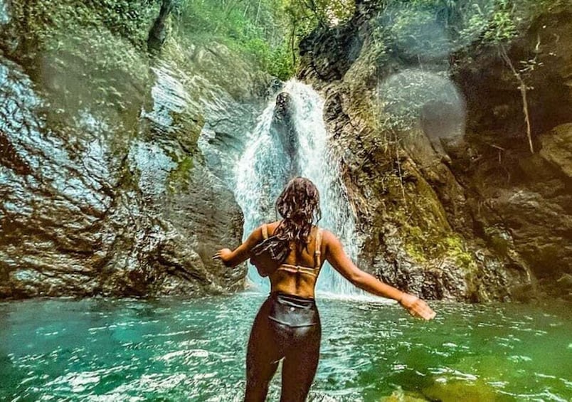 A person standing in water with a waterfall in the background. 2