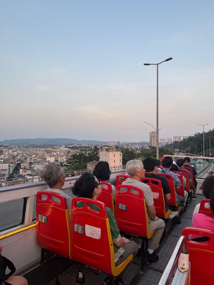 Passengers on a bus with a cityscape in the background. 3