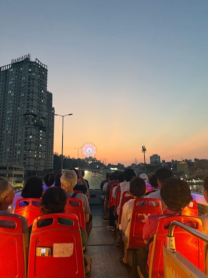 A group of people on a bus with a Ferris wheel in the background. 1