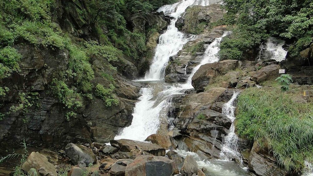 A multi-tiered waterfall surrounded by dense greenery. 2