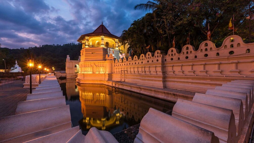 A temple with a reflection in the water, surrounded by a stone wall with arches. 1