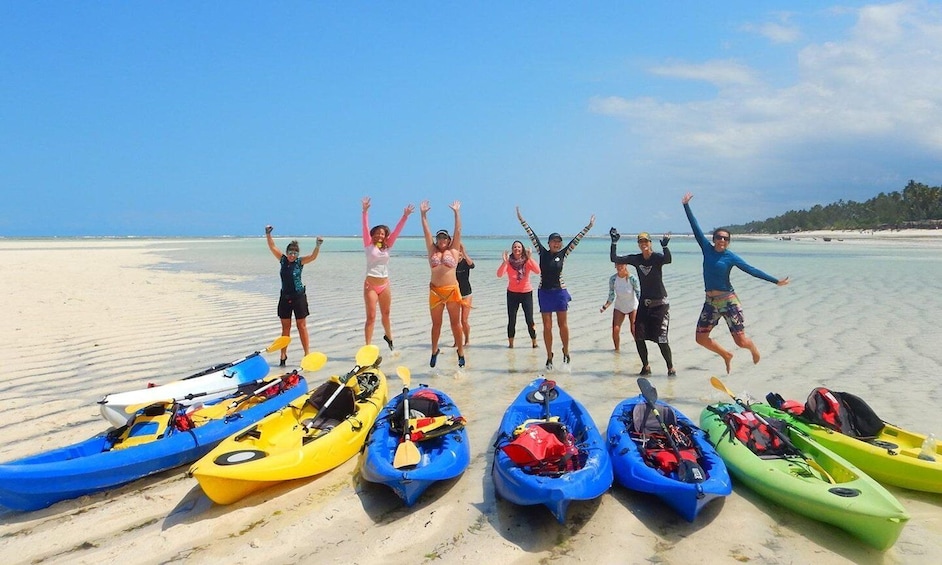 A group of people on a beach with kayaks lined up. 1