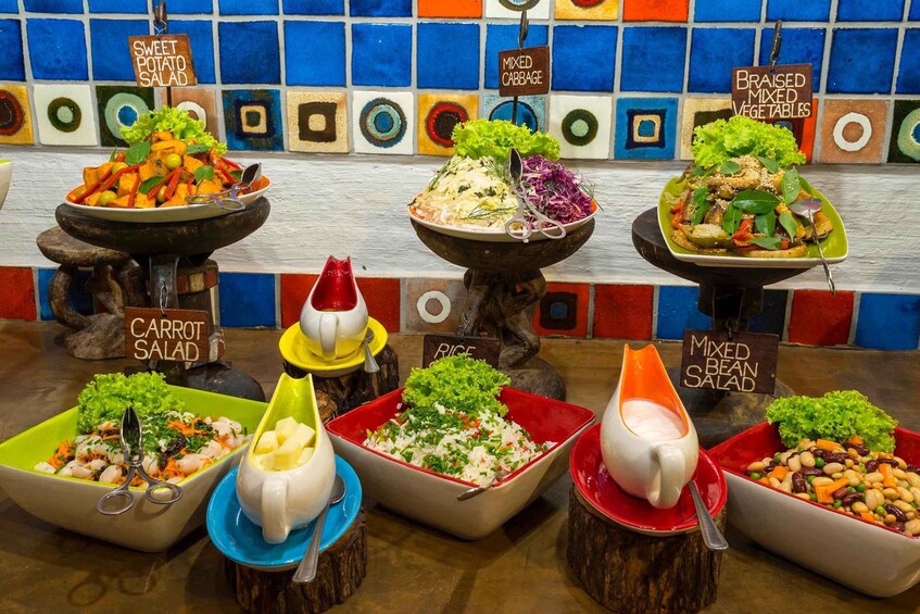 A variety of salads displayed on wooden stands with labels indicating their names. 4