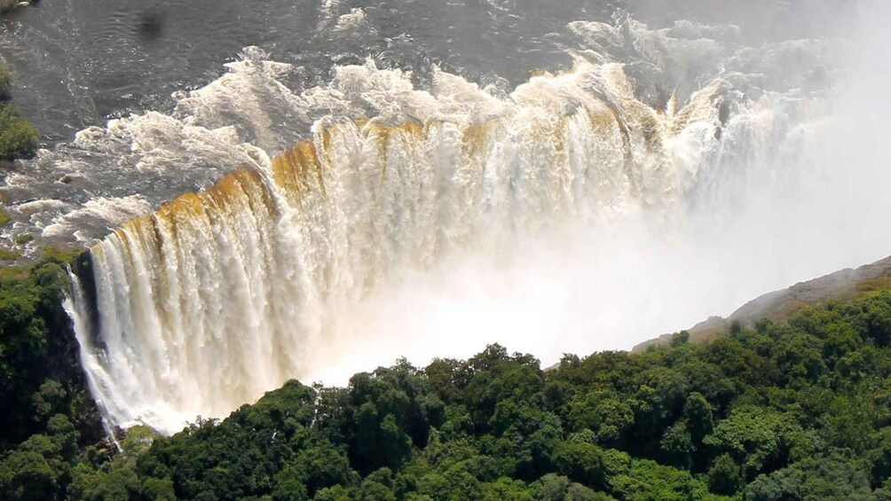A large waterfall cascading down a cliff surrounded by dense forest. 5