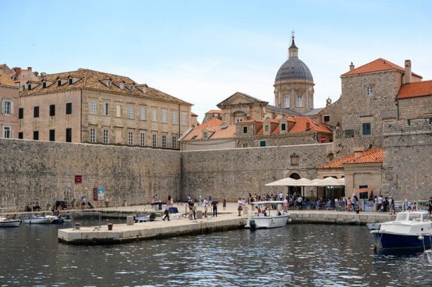 A historic waterfront with stone buildings, a dome, and boats docked. 5