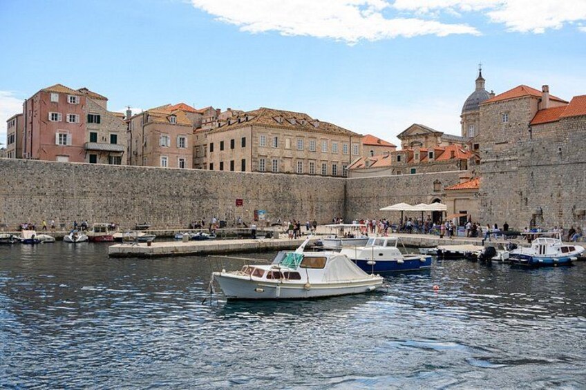 A harbor with boats, a stone wall, and historic buildings. 3