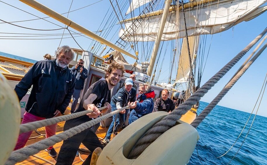 A group of people on a sailing ship, with ropes and rigging visible. 2