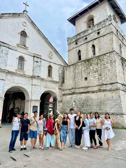 A group of people standing in front of a historic church with a bell tower. 5