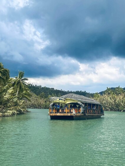 A boat with passengers, surrounded by calm water and palm trees, under a cloudy sky. 4