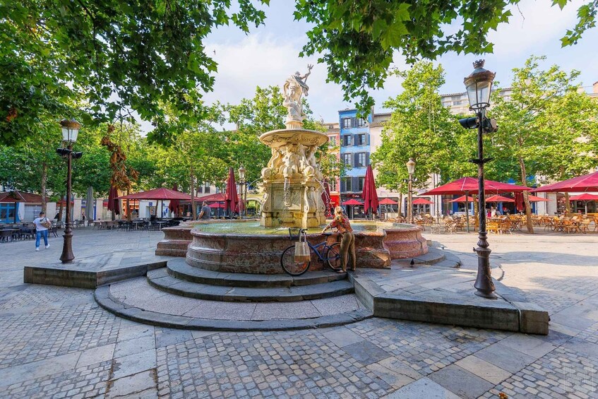 A public square with a central fountain, surrounding trees, and outdoor seating areas. 5