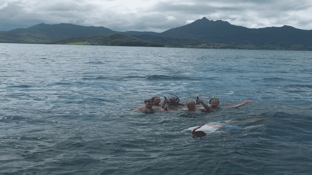 A group of people swimming in a body of water with mountains in the background. 2