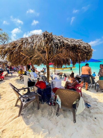 A beach with thatched umbrellas, people relaxing on chairs, and a clear blue sky. 5