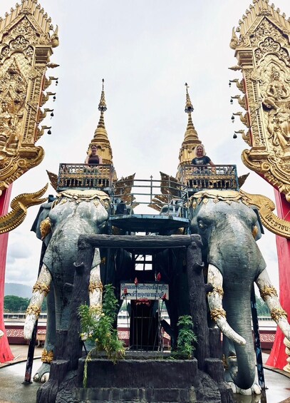 A temple entrance with golden spires and two large elephant statues. 2