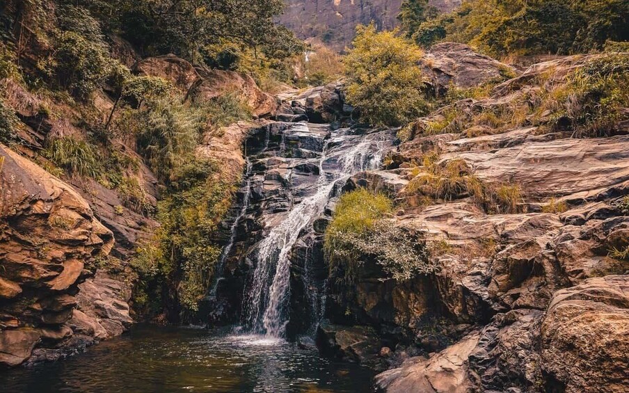 A waterfall cascading over rocky terrain surrounded by dense vegetation. 2