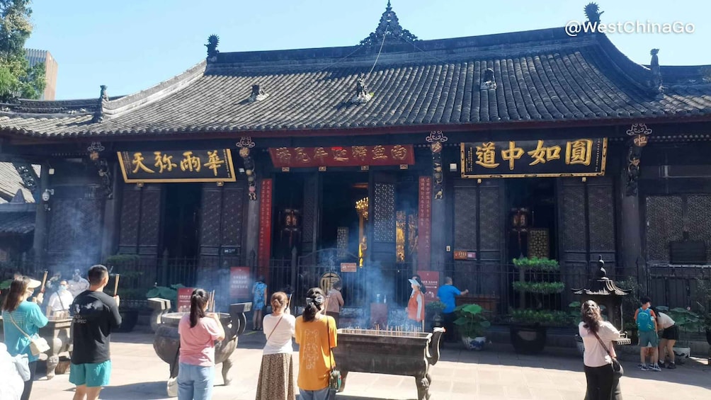 Un edificio chino tradicional con decoraciones elaboradas y un quemador de incienso grande al frente. 4