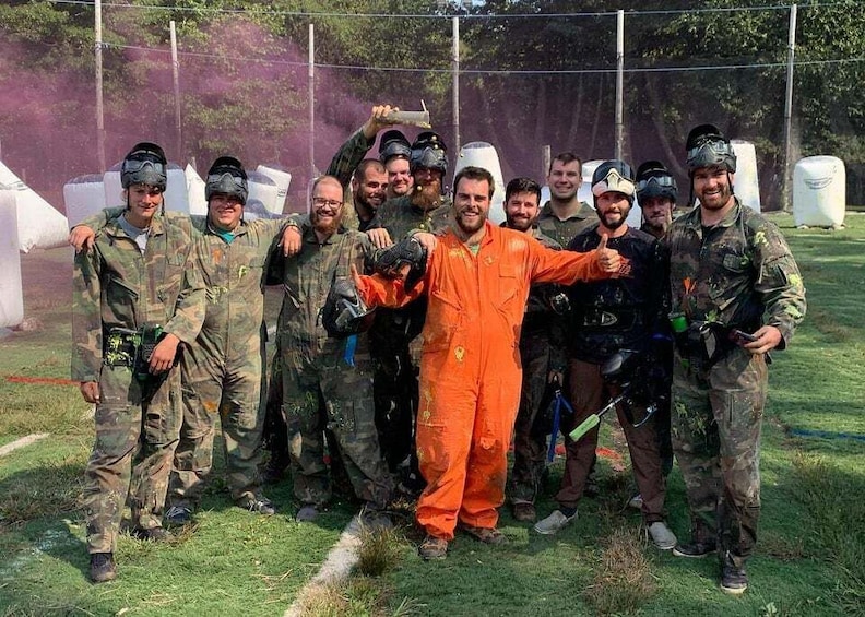 A group of people in military and orange jumpsuit attire posing for a photo in an outdoor setting with trees and a fence in the background. 1