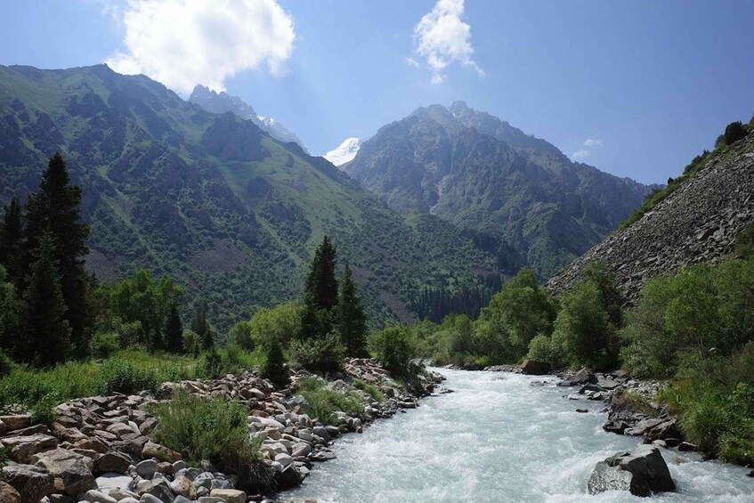 A river flowing through a mountainous landscape with rocky banks and dense greenery. 3