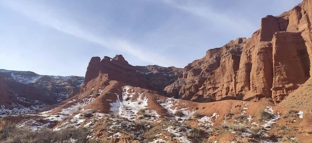 A rugged desert landscape with red rock formations and patches of snow. 4