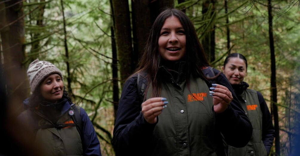 Three people in a forested area, wearing vests with 'PLAYERY TEAM' text. 1