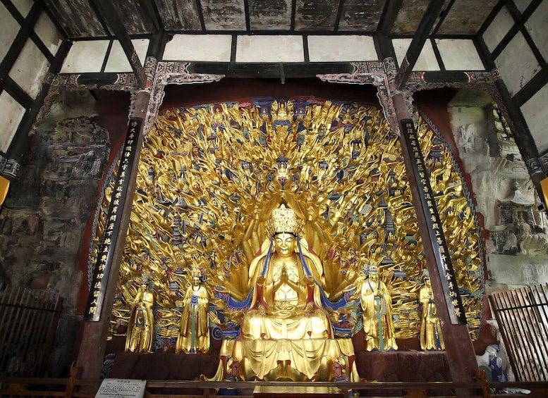A large golden Buddha statue surrounded by numerous smaller golden statues in a temple. 4