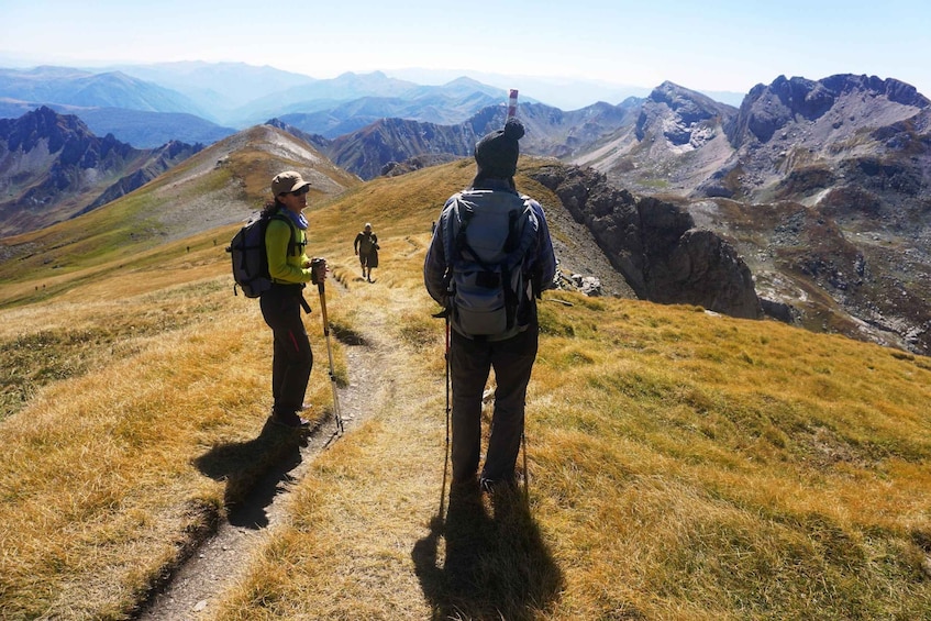 Hikers on a mountain trail with a view of distant mountains. 5