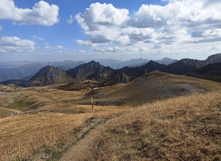 A mountainous landscape with a clear sky and a trail marked by a red and white sign. 2