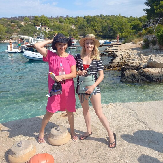 Two people standing by a rocky waterfront with boats in the background. 5