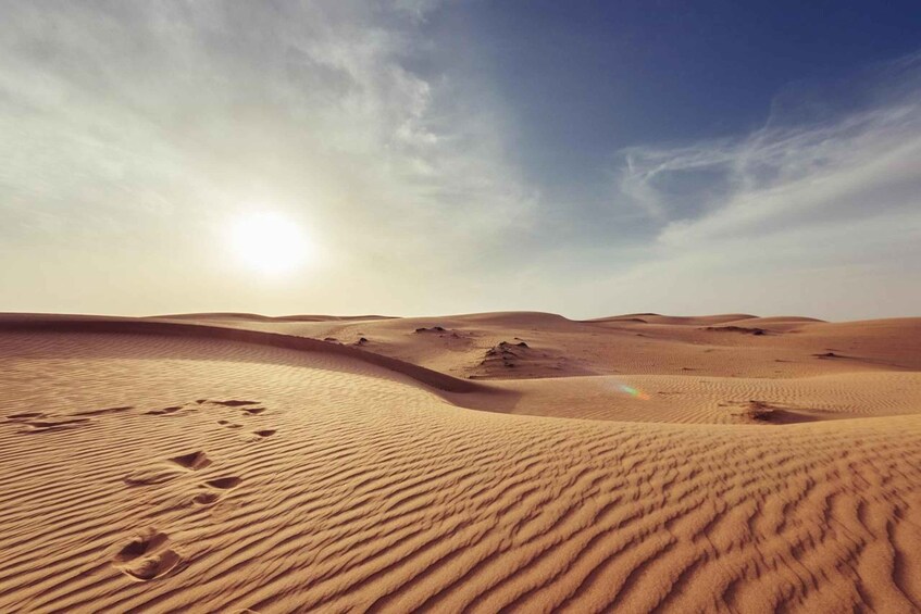 A desert landscape with sand dunes and footprints. 4