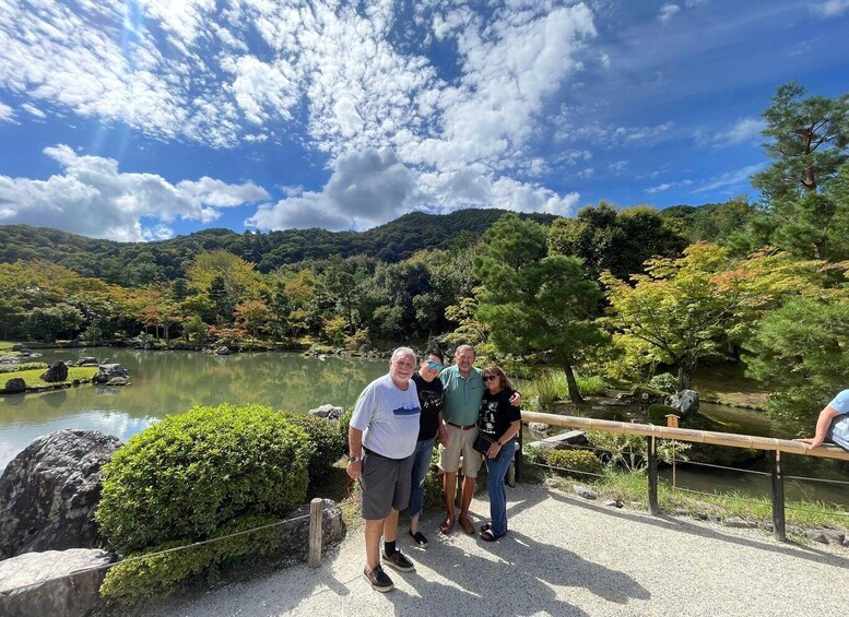 A group of people standing by a lake with a wooden fence, surrounded by trees and hills. 5