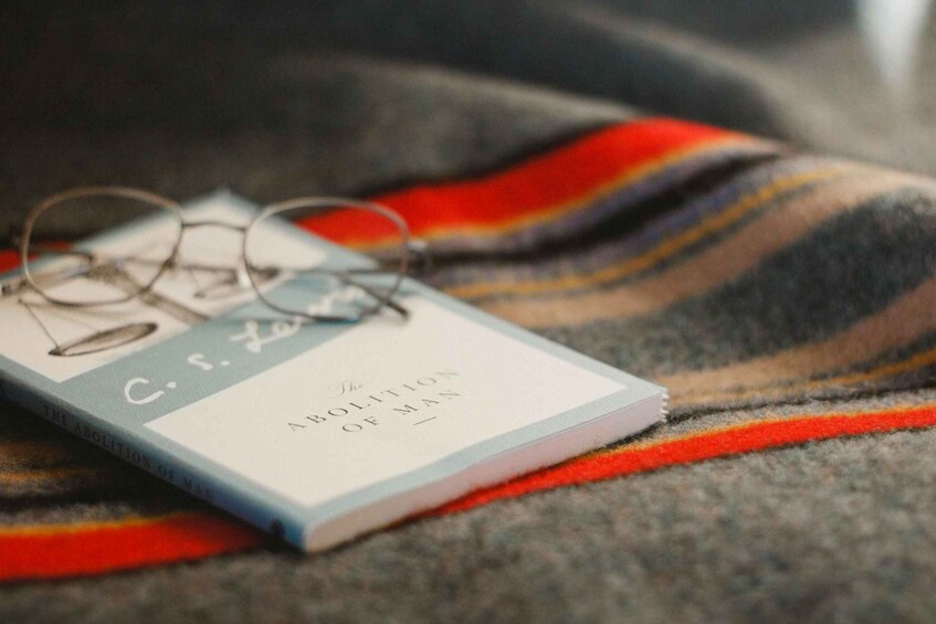 A book titled 'The Abolition of Man' by C. S. Lewis on a striped fabric. 5