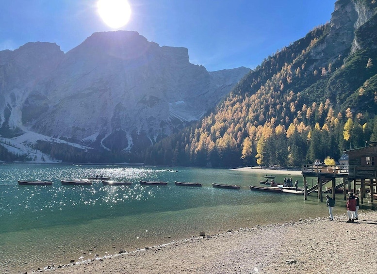 A calm lake with boats, a wooden dock, and a mountainous backdrop. 1