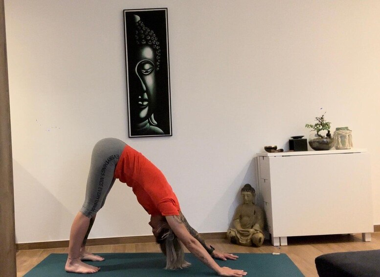 A person performing a yoga pose on a mat in a room with a statue and a painting on the wall. 3